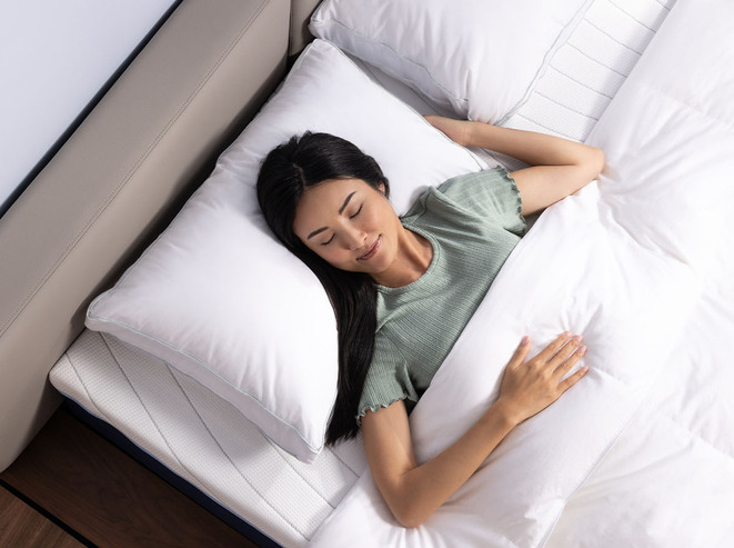 A woman sleeping on her stomach, with her head resting on a Memory Foam Pillow from Octave.